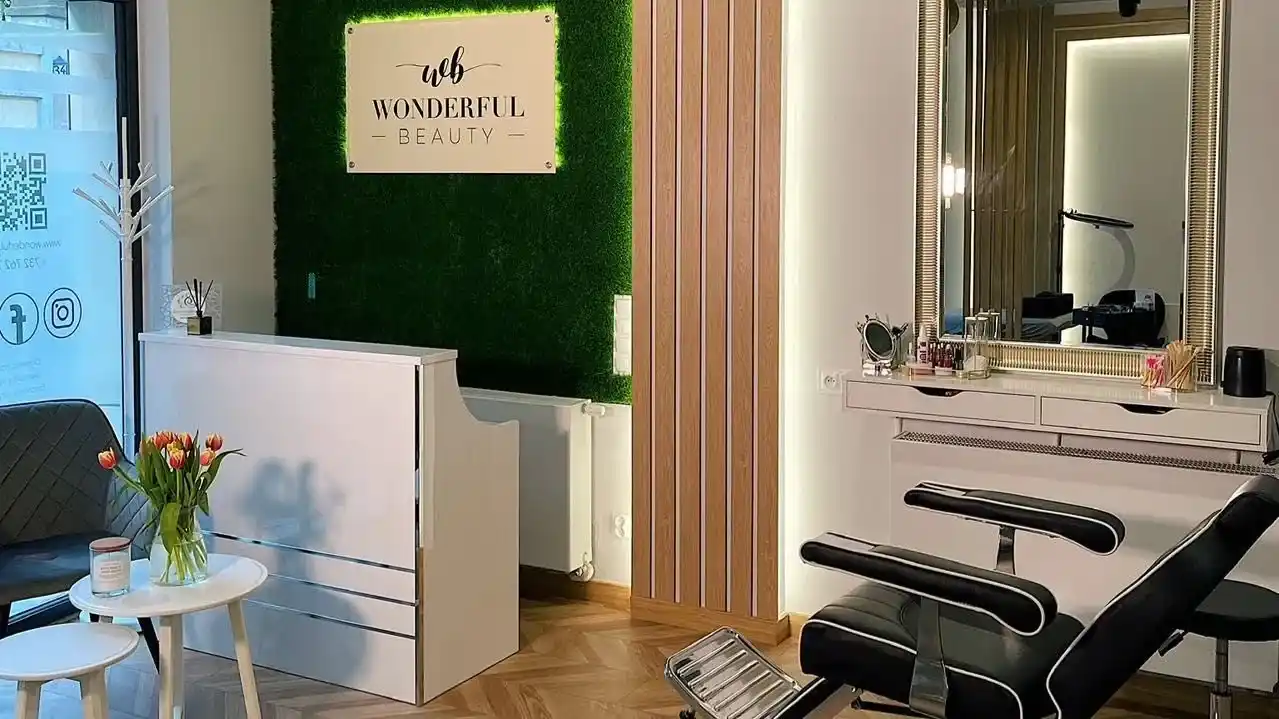 Wnętrze salonu Wonderful Beauty — zielona ściana z logo, ciepłe drewno, Poznań